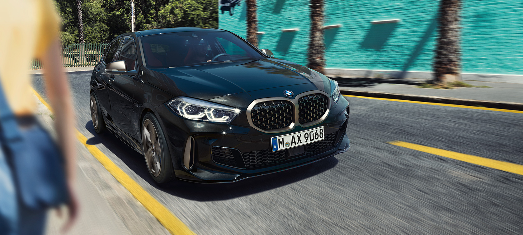 BMW M135i xDrive en Black Sapphire metallic, vista frontal de tres cuartos en movimiento.