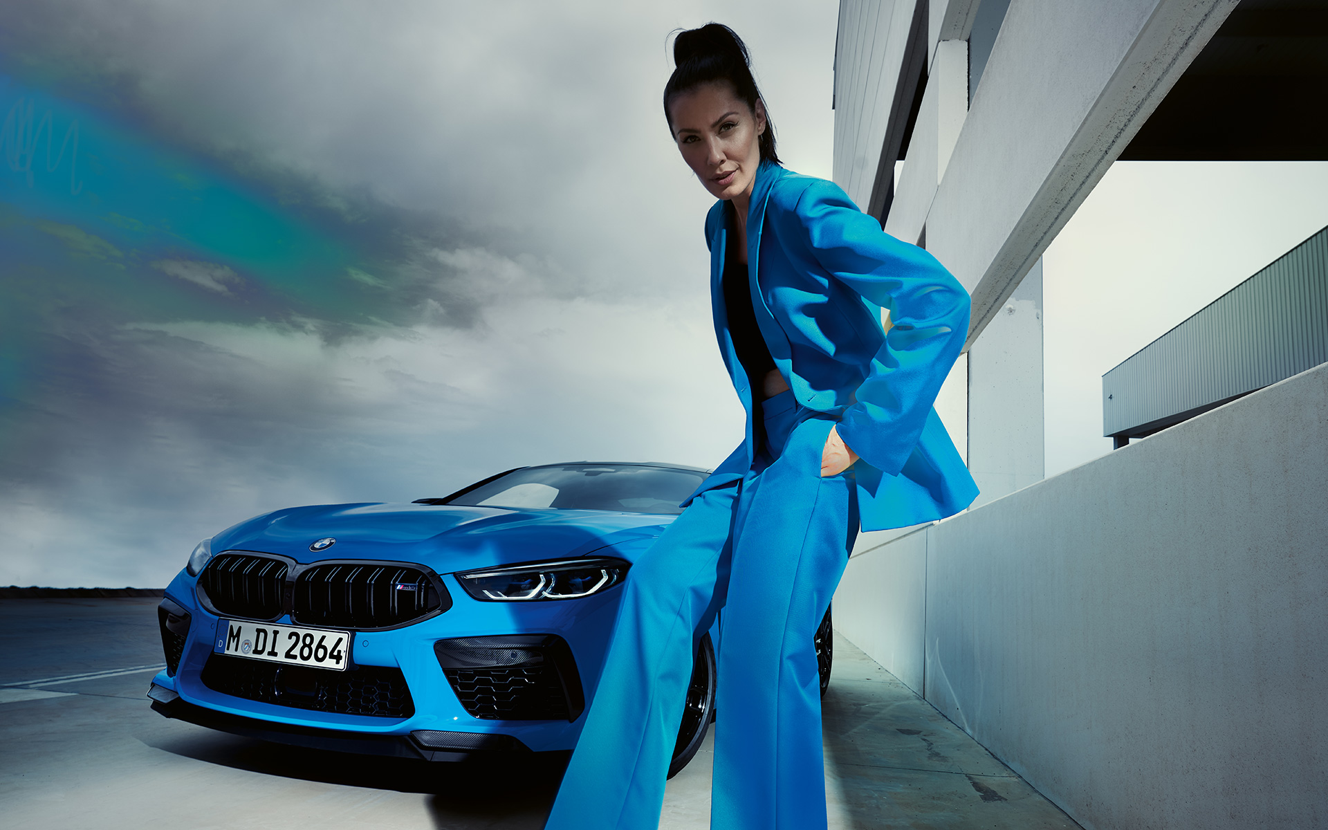 Nuevo BMW M8 Competition Coupé F92 LCI Renovación 2022 Daytona Beach Blue sólido, vista de tres cuartos del frontal, modelo femenina con traje pantalón azul