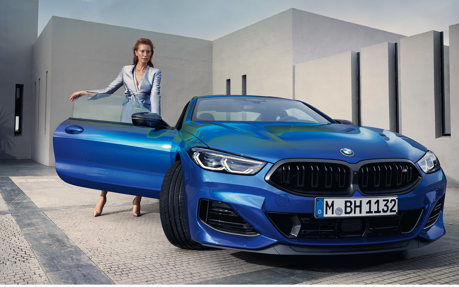 Nuevo BMW M850i xDrive Coupé G15 LCI Renovación 2022 M Portimao Blue metalizado, vista del frontal, parado, con modelo femenina en la puerta abierta del acompañante