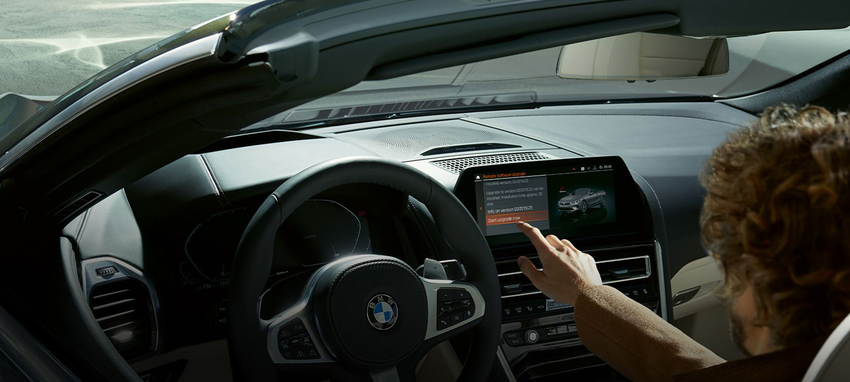 Un hombre se sienta en un BMW e inicia BMW Remote Software Upgrade